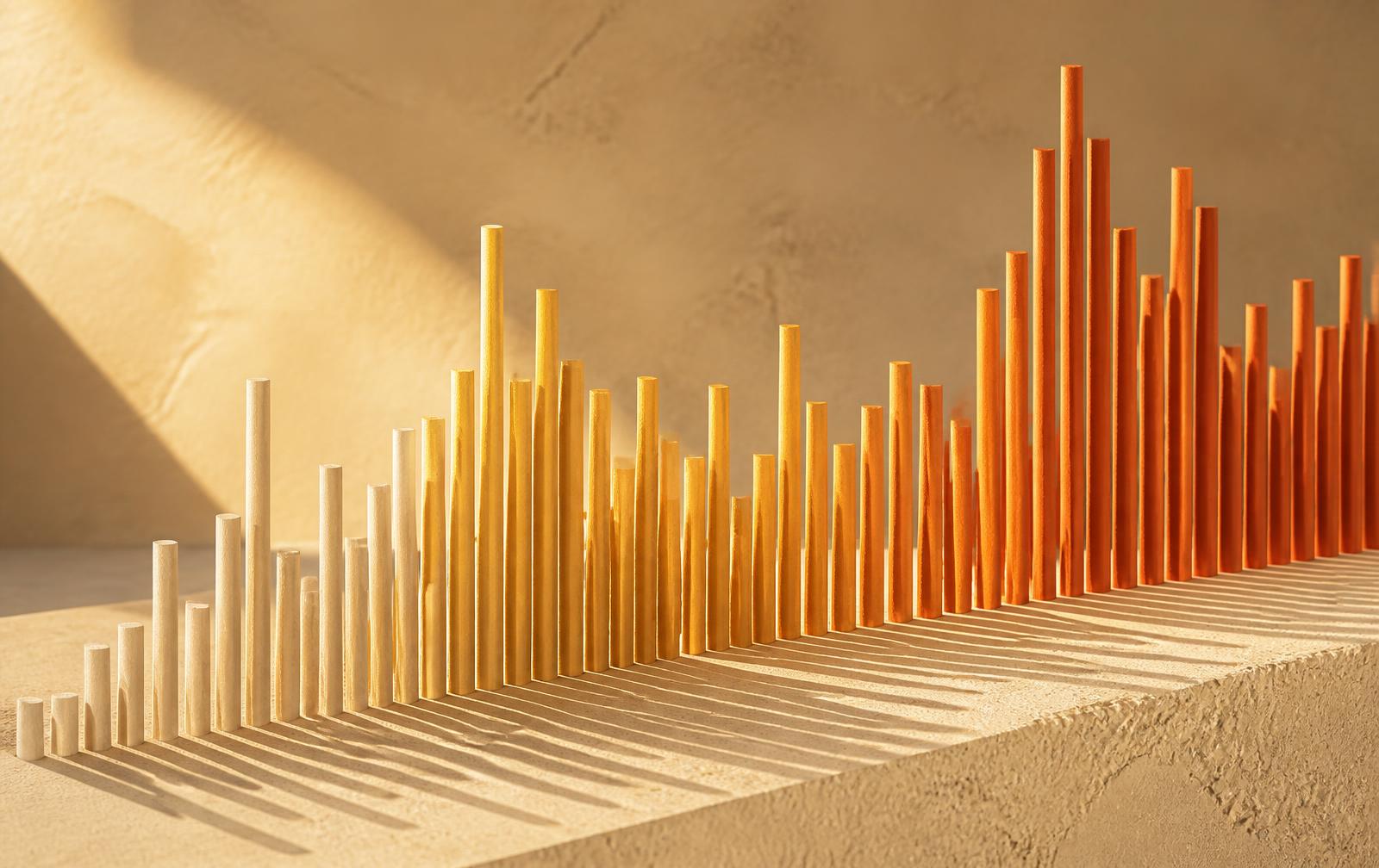 Abstract chart formed from wooden rods of varying heights casting long shadows in warm light